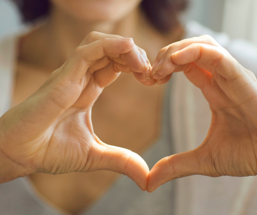 A person’s hands forming the shape of a heart, held close to their chest—symbolizing a culture of gratitude. The background is softly blurred, focusing on the hands and heartfelt gesture.