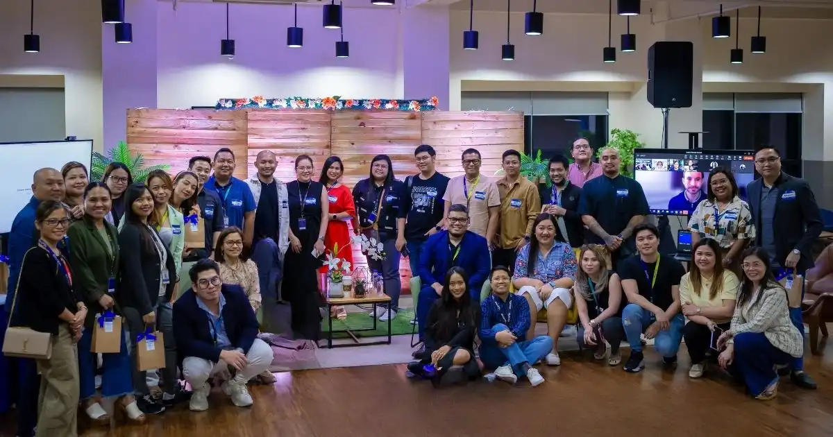 A large group of people from Emapta pose together indoors, smiling at the camera. The festive setting with plants, lights, and a decorated wooden backdrop highlights their innovative culture and celebration of WorkLife Awards.