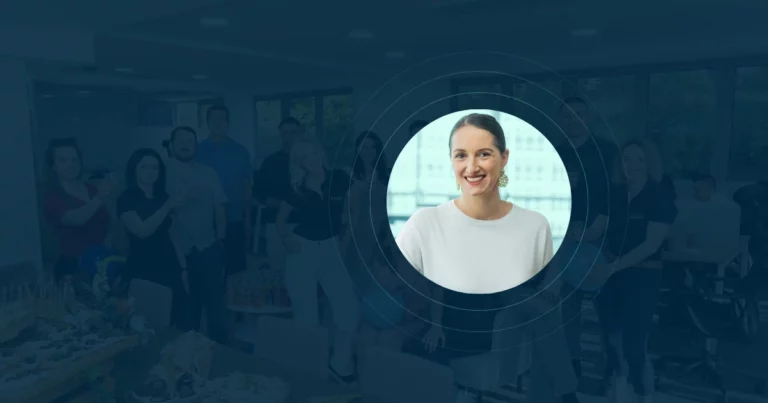 A group of people posing and smiling in an office, with a circular cutout highlighting a woman in a white top, smiling at the camera, centered in the foreground—perfect for discussing B Corp Certification on a podcast.